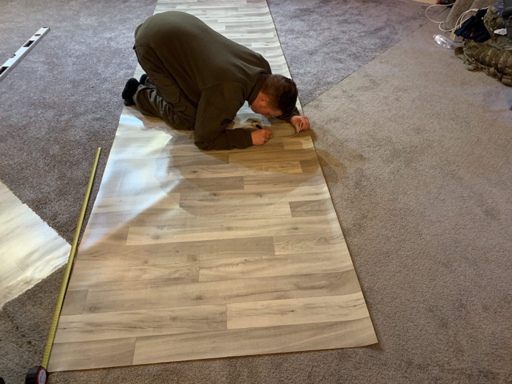 Alex Clowes Mission Ukraine / Actions beyond words, prepares lino for fitting to the kitchen area.