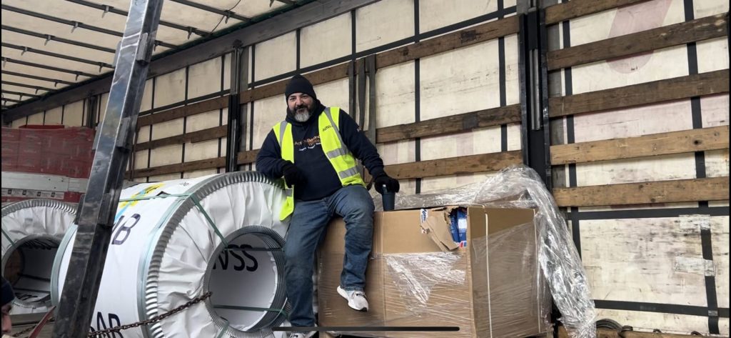 Travis Goode taking a short break, sitting on the final box of Humanitarian Aid to offload, a donation from our amazing friends at NADA-NORD, Finland